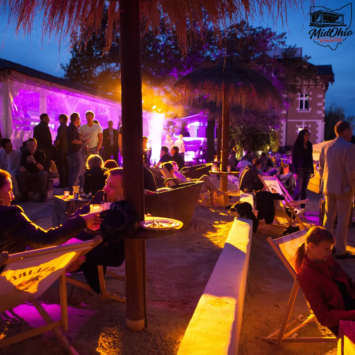 Guests enjoying an evening outdoor event lit by stage lighting