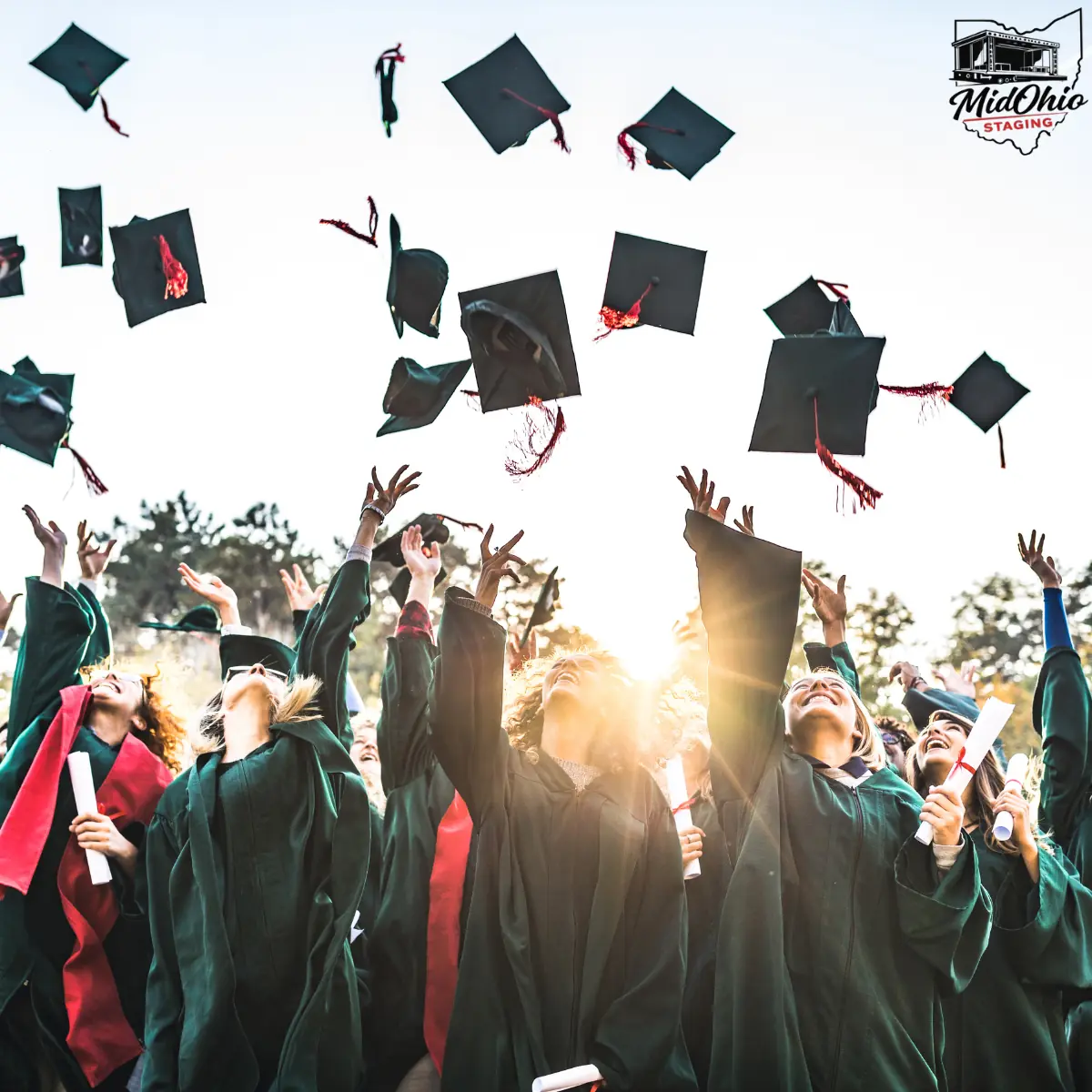 Graduates tossing caps in the air at an outdoor graduation ceremony