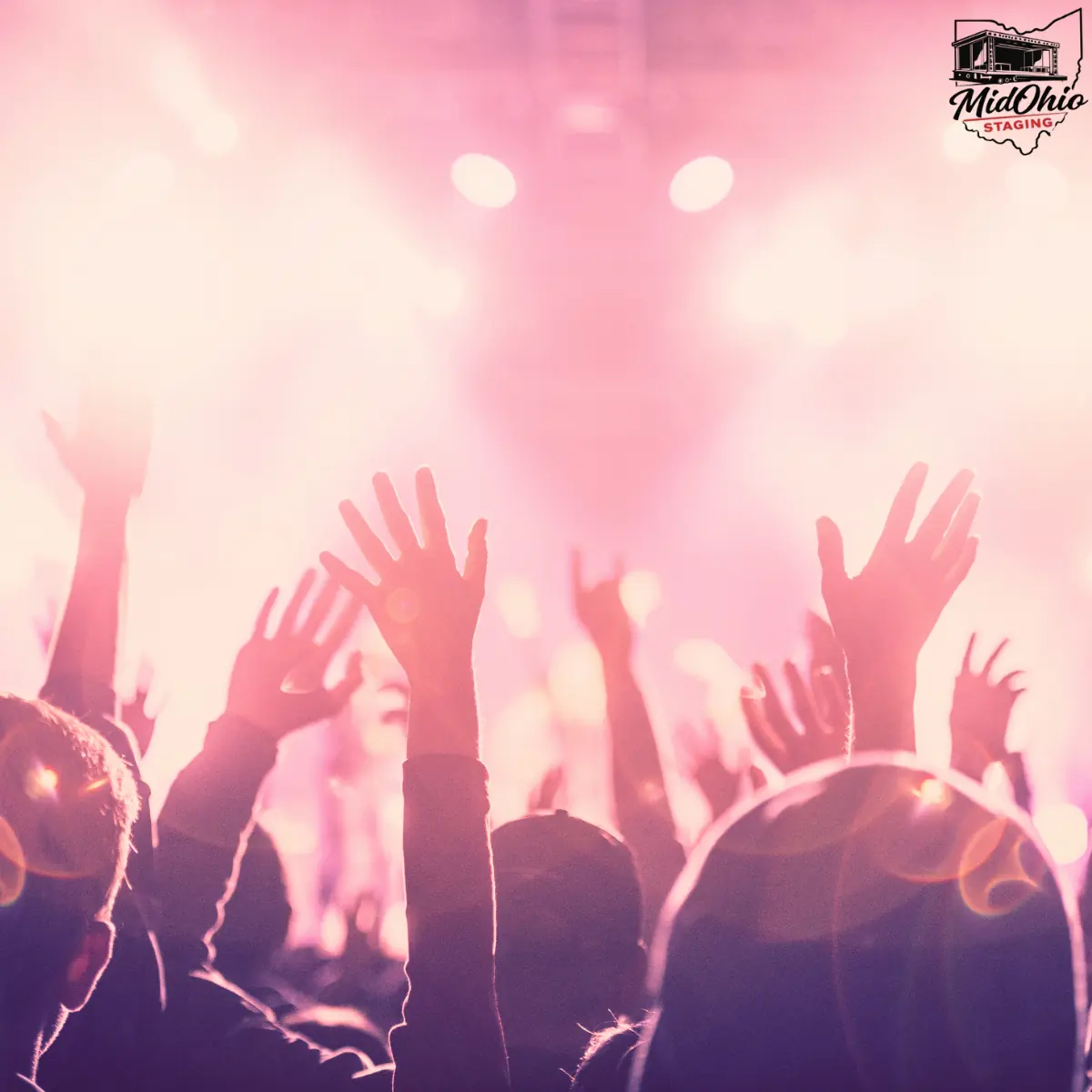 Concert crowd with hands raised in front of a stage